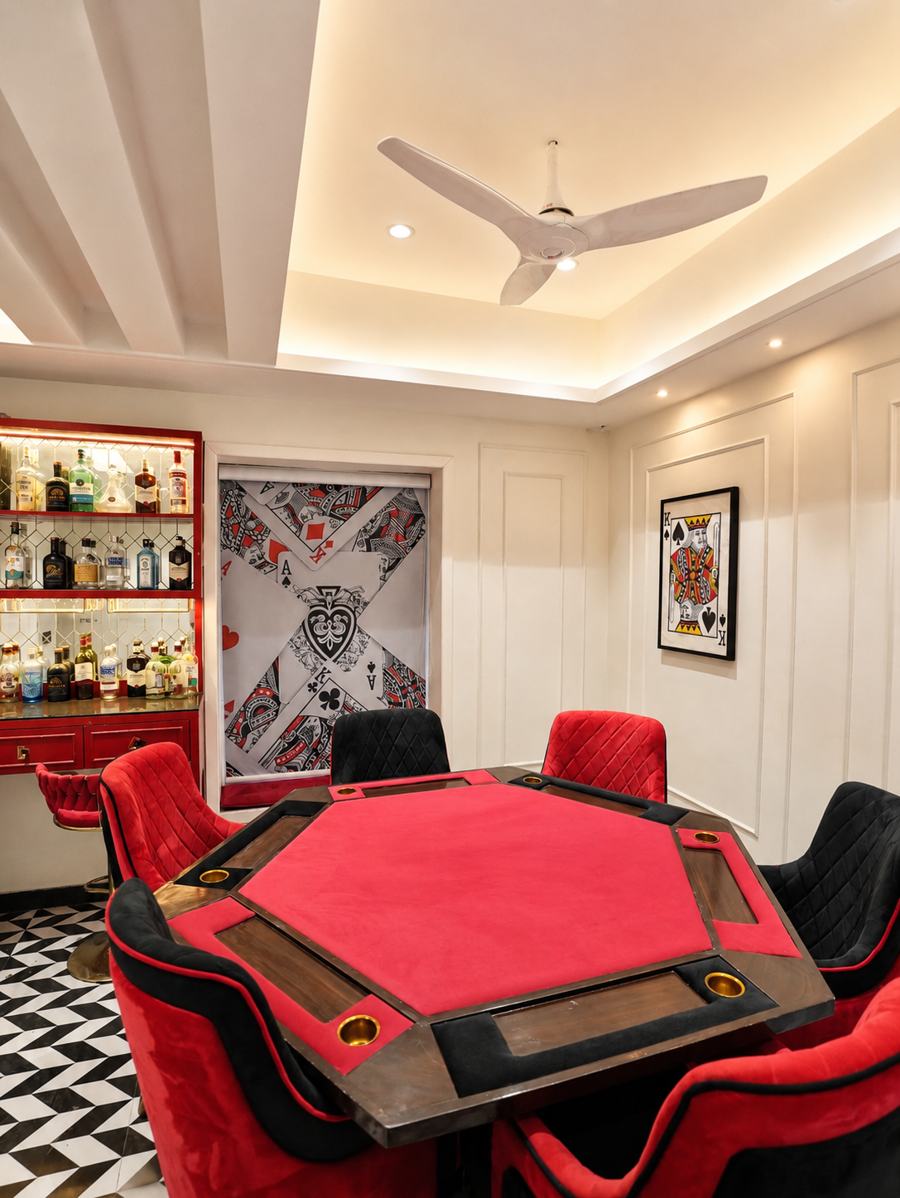 Red felt poker table surrounded by velvet chairs
